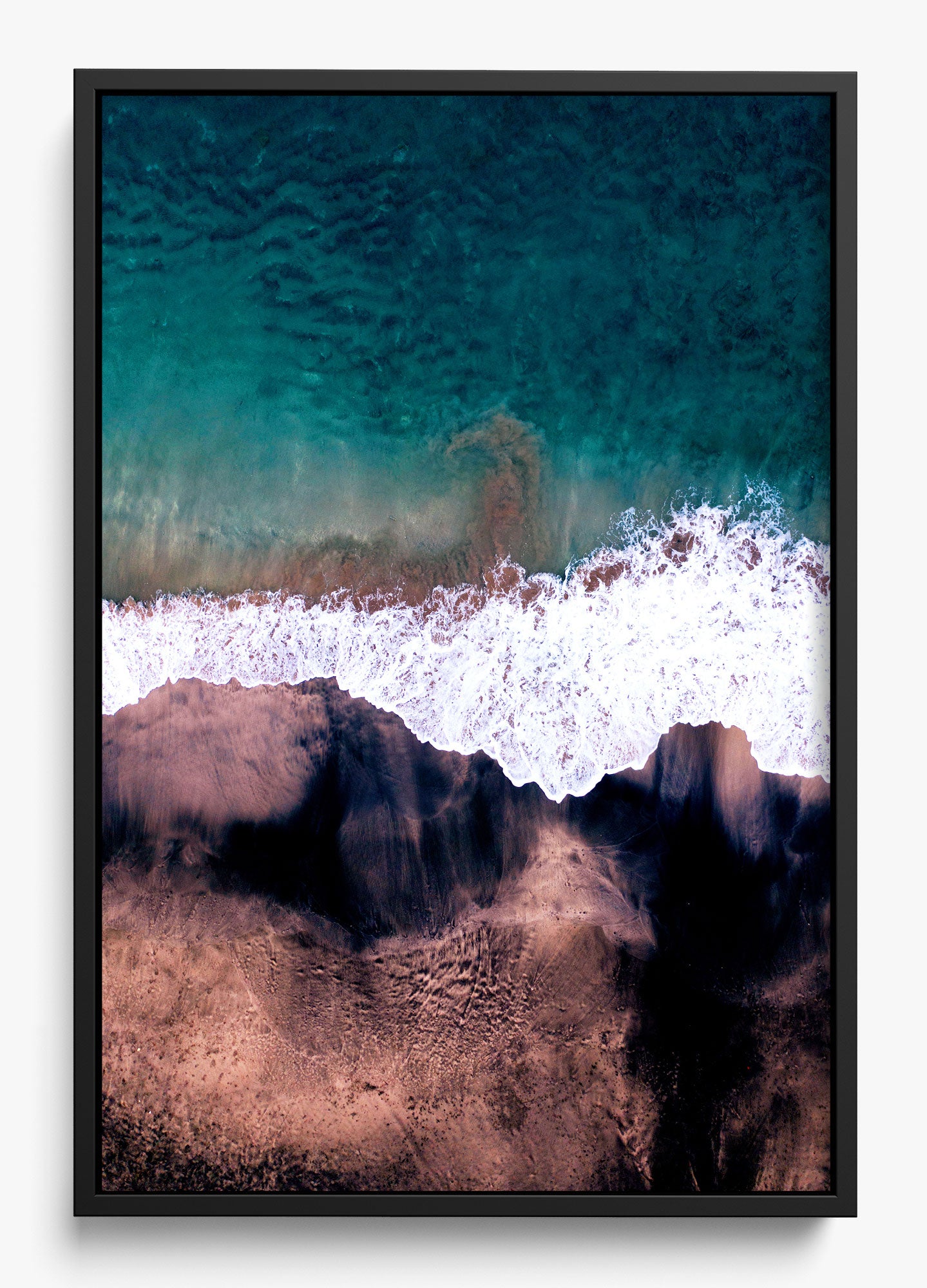 Black and blue wall decor featuring an aerial view of a beach with waves crashing on a sandy shore.