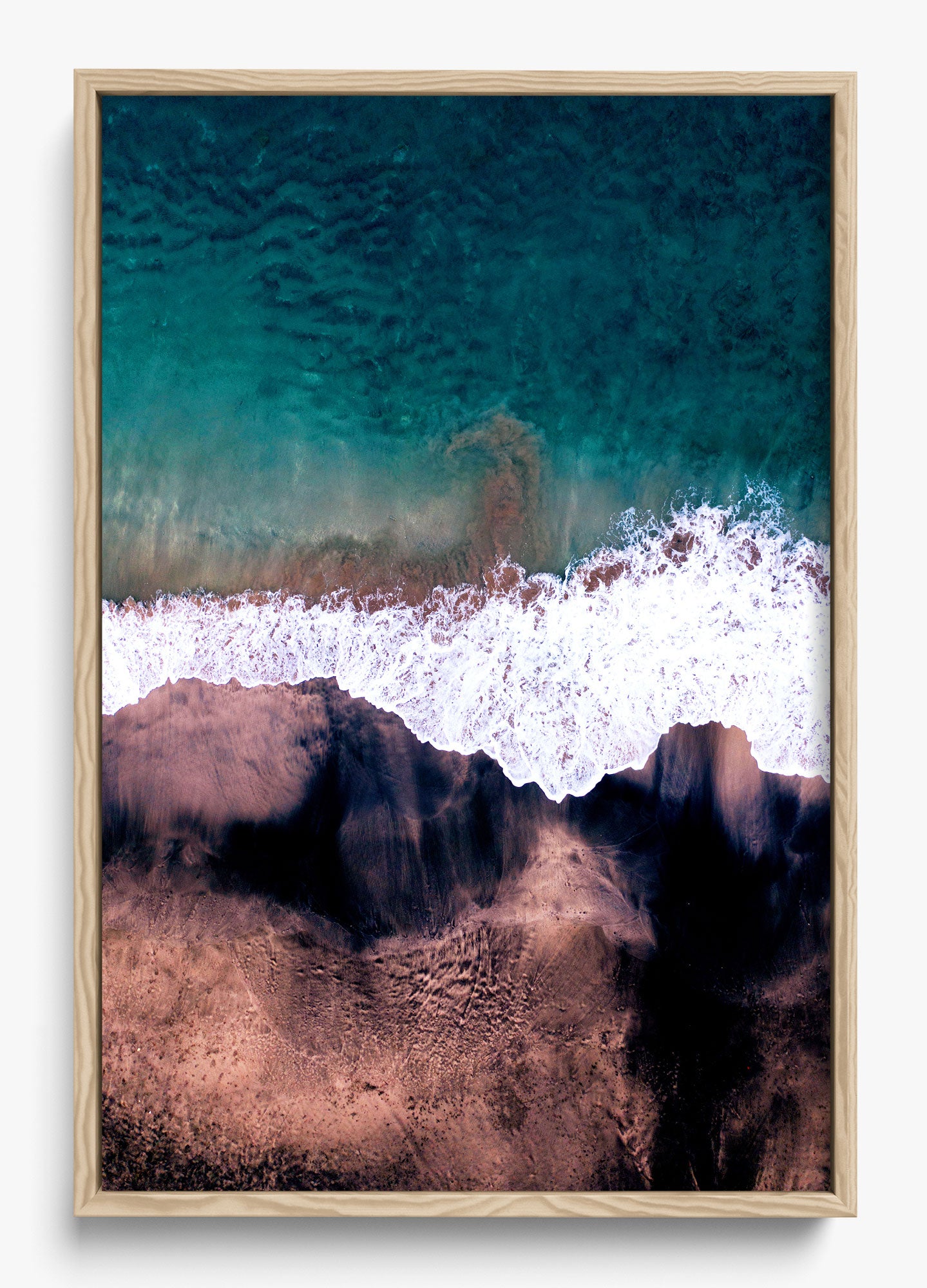 Black and blue wall decor featuring an aerial view of ocean waves meeting sandy shore in a wooden frame.