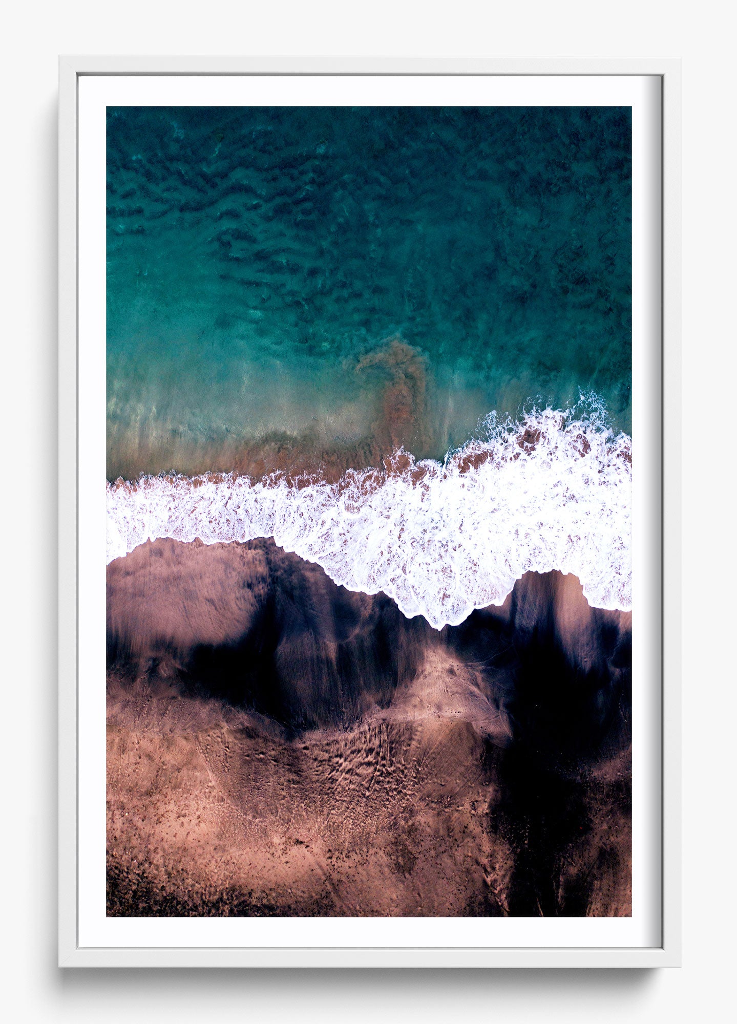 Framed wall decor featuring an aerial view of a black and blue ocean with waves crashing on the shore.